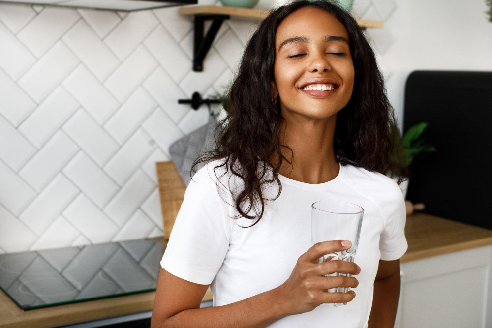 pretty-afro-woman-holds-a-glass-of-water-and-has-happy-look