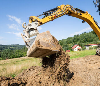 Mini excavator digging preparing ground under home garden